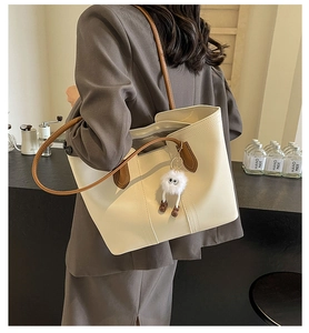 Maillard style tote bag in beige with brown straps worn by a model in a coffee shop