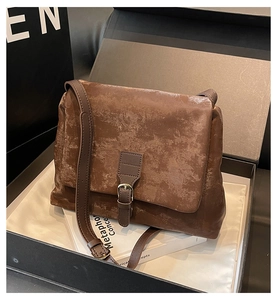 Close-up of brown vintage tote bag with metal buckle on velvet padding in gift box
