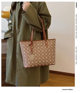 Grand sac cabas marron à monogramme porté avec un trench-coat vert foncé
