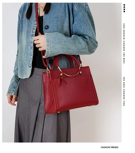 Detailed shot of red lychee grain leather handbag with metal ring handle and strap