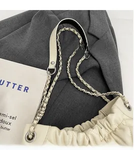 Detail of cream pleated cloud bag featuring silver metal chain and wide leather strap