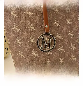 Gros plan sur l'imprimé Pégase doré sur cuir marron avec un pendentif en métal lettre M