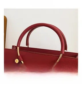 Macro detail of red lychee grain leather wedding bag with golden circular metal handle