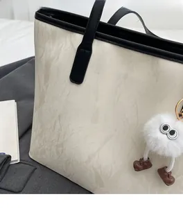 Detail of marble texture tote bag with black faux leather trim and fuzzy monster charm