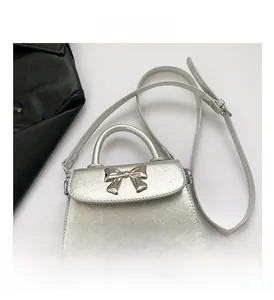 Detail view of silver cracked leather mini square bag with metal bow and top handle