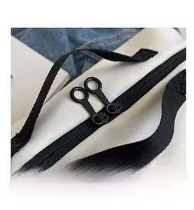 Close-up of smooth black double zipper on white oxford cloth crossbody bag