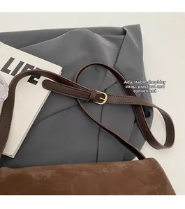 Close-up of adjustable shoulder strap with gold metal buckle on brown tote bag