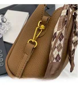 Close-up of litchi pattern leather bag with gold hardware and checkered silk scarf