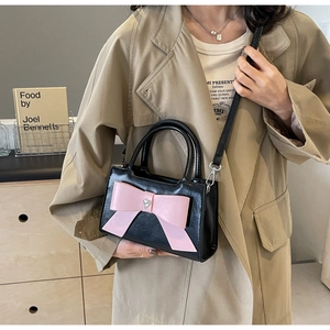 Close-up of black PU leather bag featuring a large pink bow and heart-shaped diamond