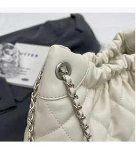Detailed view of silver chain strap and white quilted leather texture on bucket bag