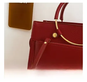 Detail of red leather bridal bag featuring gold metal rings and a smooth zipper puller