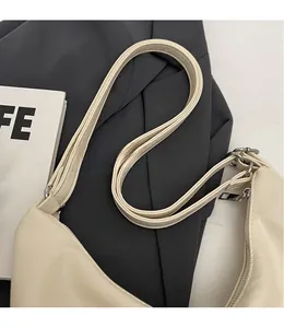 Detail of a creamy white faux leather bag with silver metal rings and smooth shoulder strap