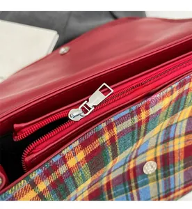 Close-up of silver metal zipper and plaid fabric lining on a red leather tote bag