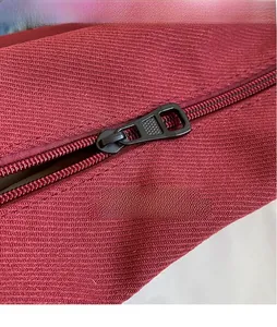 Macro detail of high-quality black metal zipper on red textured canvas hobo bag