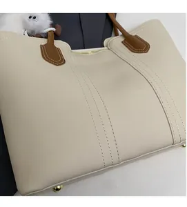Detail view of cream tote bag base with double stitching and golden metal protective studs