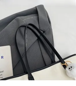 Detail of a black and white tote bag with faux fur eye charm and durable leather straps