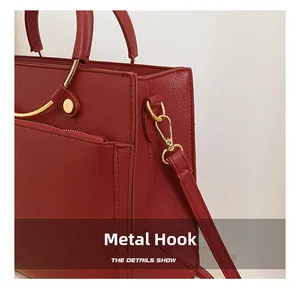 Detail of red pebbled leather bag featuring golden hardware hooks and neat stitching