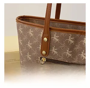 Détail du sac cabas imprimé Pégase montrant le zip en métal et la poignée en cuir brun
