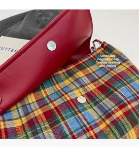 Detailed close-up of a plaid tote bag showing the magnetic closure and red flap detail