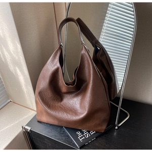 Détail du sac hobo marron montrant la texture du cuir grainé sous une lumière naturelle