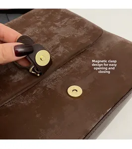 Detail of vintage brown tote bag featuring golden magnetic snap closure and textured finish