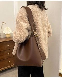 Vue détaillée du grand sac seau en cuir marron foncé avec large bandoulière à œillets