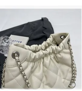 Close-up of quilted cream bucket bag featuring drawstring closure and silver chain strap