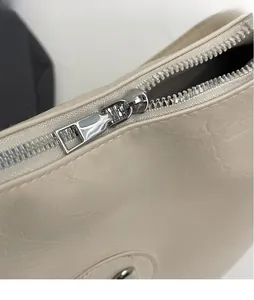 Close-up of sleek silver zipper and cream pleated faux leather texture on the handbag