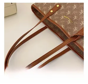 Détail de la poignée du sac cabas marron avec rivets dorés et motif Pégase