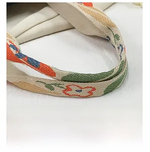 Gros plan sur l'anse tissée épaisse avec motifs floraux colorés du sac fourre-tout