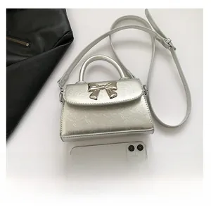 Detailed top view of a silver textured mini bag with gold bow next to a smartphone