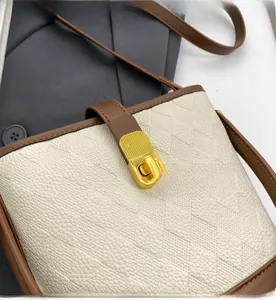 Détail du fermoir doré sur le sac seau en cuir beige matelassé avec bandoulière marron