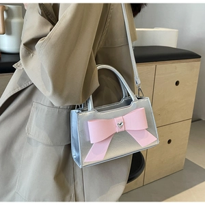 Detailed shot of silver handbag featuring a pink bow with a heart-shaped crystal