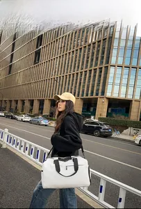 Photo de rue d'un grand sac de voyage blanc en Oxford avec des lanières noires en ville