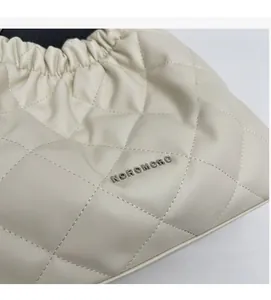 Close-up of beige quilted bucket bag showing leather texture and metal logo detail