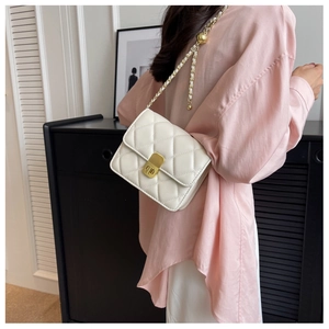 Macro view of white quilted faux leather bag with gold clasp and chain strap adjustment