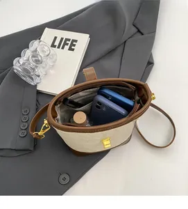 Vue intérieure du petit sac seau beige montrant la capacité pour téléphones et maquillage