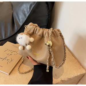 Detailed macro of crocodile pattern leather on beige cloud bag with gold chain strap