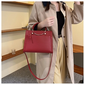 Red bridal shoulder bag with metal handle styled with a classic beige trench coat