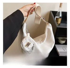 Détail du sac croissant blanc cassé avec une bandoulière large et un petit porte-monnaie