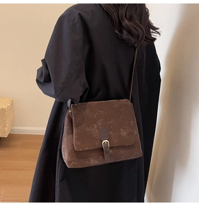 Detail of dark brown frosted leather tote bag with vintage metal buckle and strap