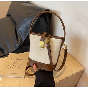 Détail d'un sac seau tissé avec bordure en cuir marron et fermoir métallique doré