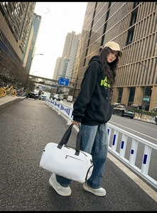 Détail d'un grand sac de voyage blanc en tissu Oxford porté par un mannequin au style urbain