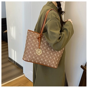 Sac cabas marron à motif Pégase avec pendentif doré M porté à l'épaule du mannequin