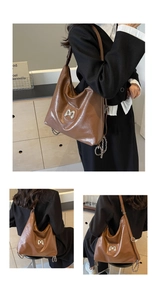 Detail of glossy brown PU leather texture and silver M-shaped metal hardware on the bag