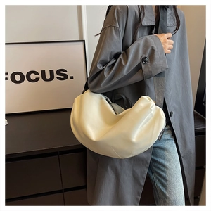Detail of off-white dumpling bag with wide black strap and premium leather texture