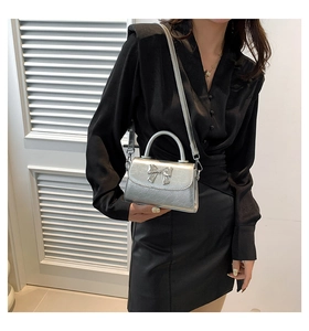 Silver metallic mini handbag featuring a decorative bow and detachable long shoulder strap