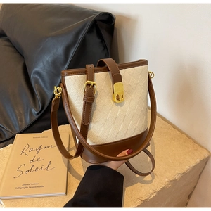 Détails d'un sac seau vintage avec matelassage beige et finitions en cuir marron