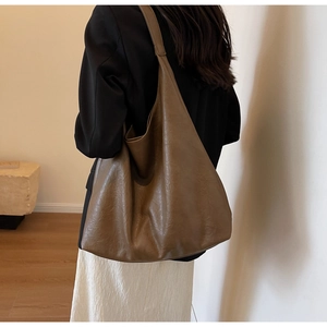 Grand sac hobo marron à texture mate porté par un mannequin dans un cadre chaleureux