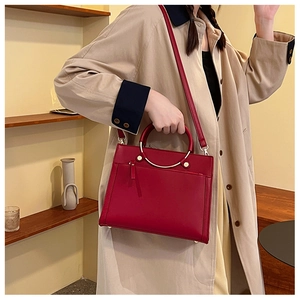 Detail of red bridal handbag featuring golden ring handles and premium leather texture